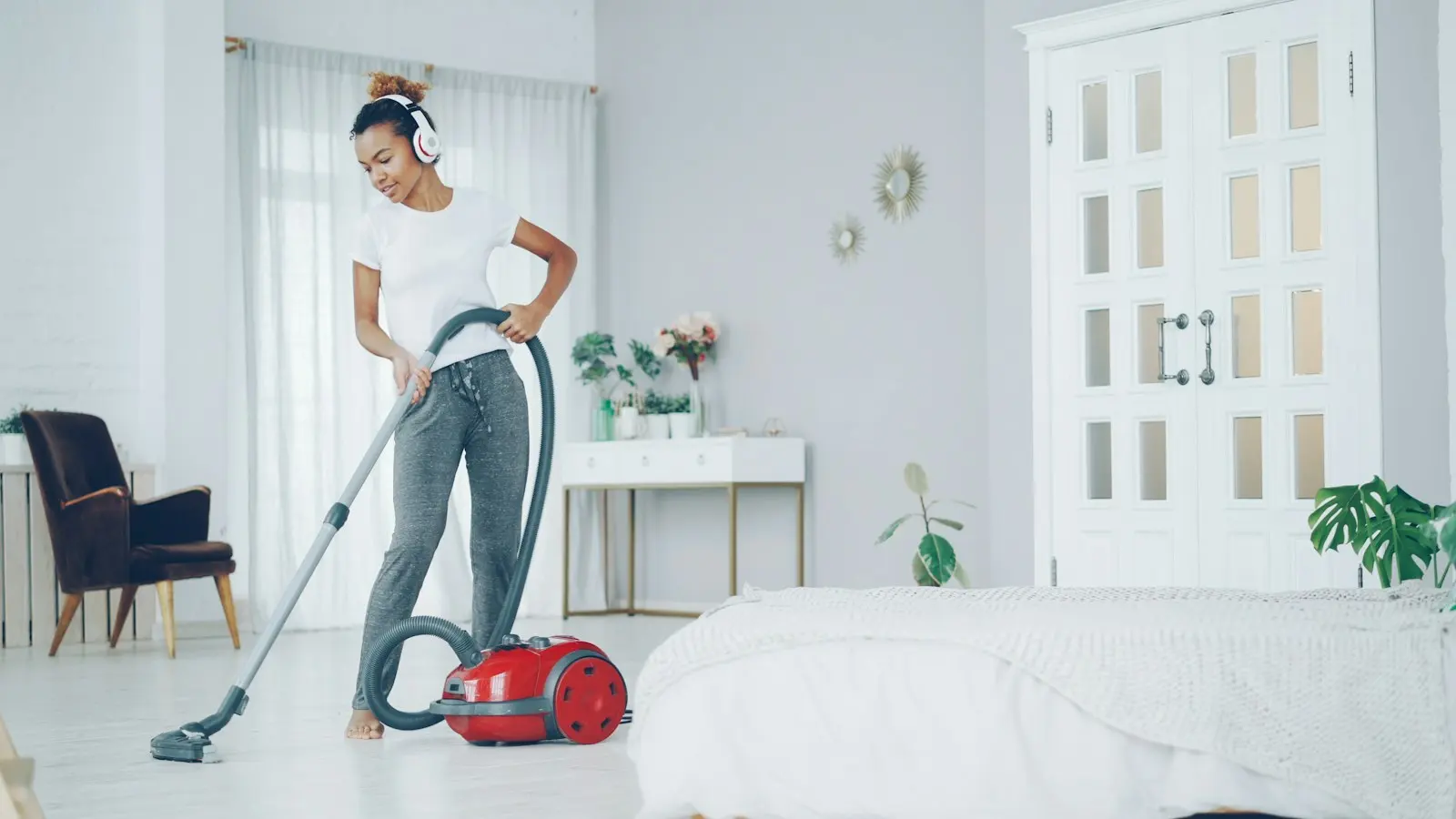 A cleaner vacuuming a bright bedroom